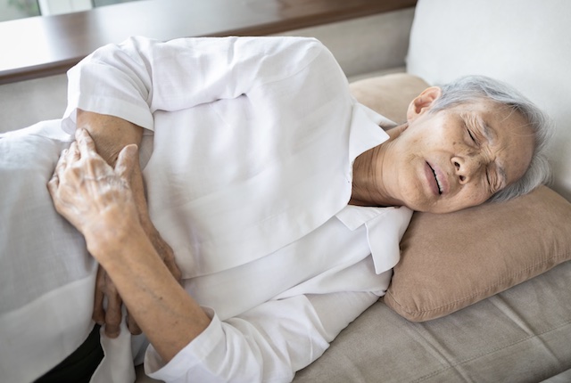 腹部を押さえる高齢者